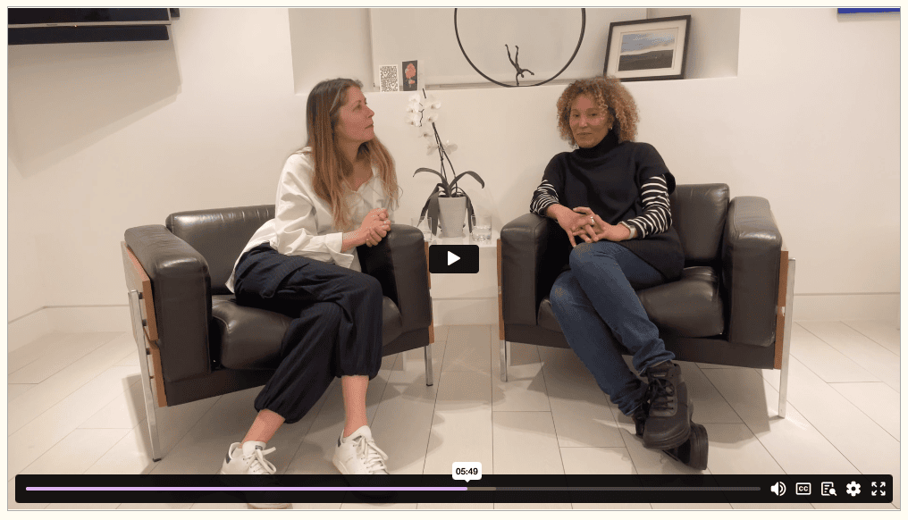 A video player shows two women sitting in chairs talking to each other